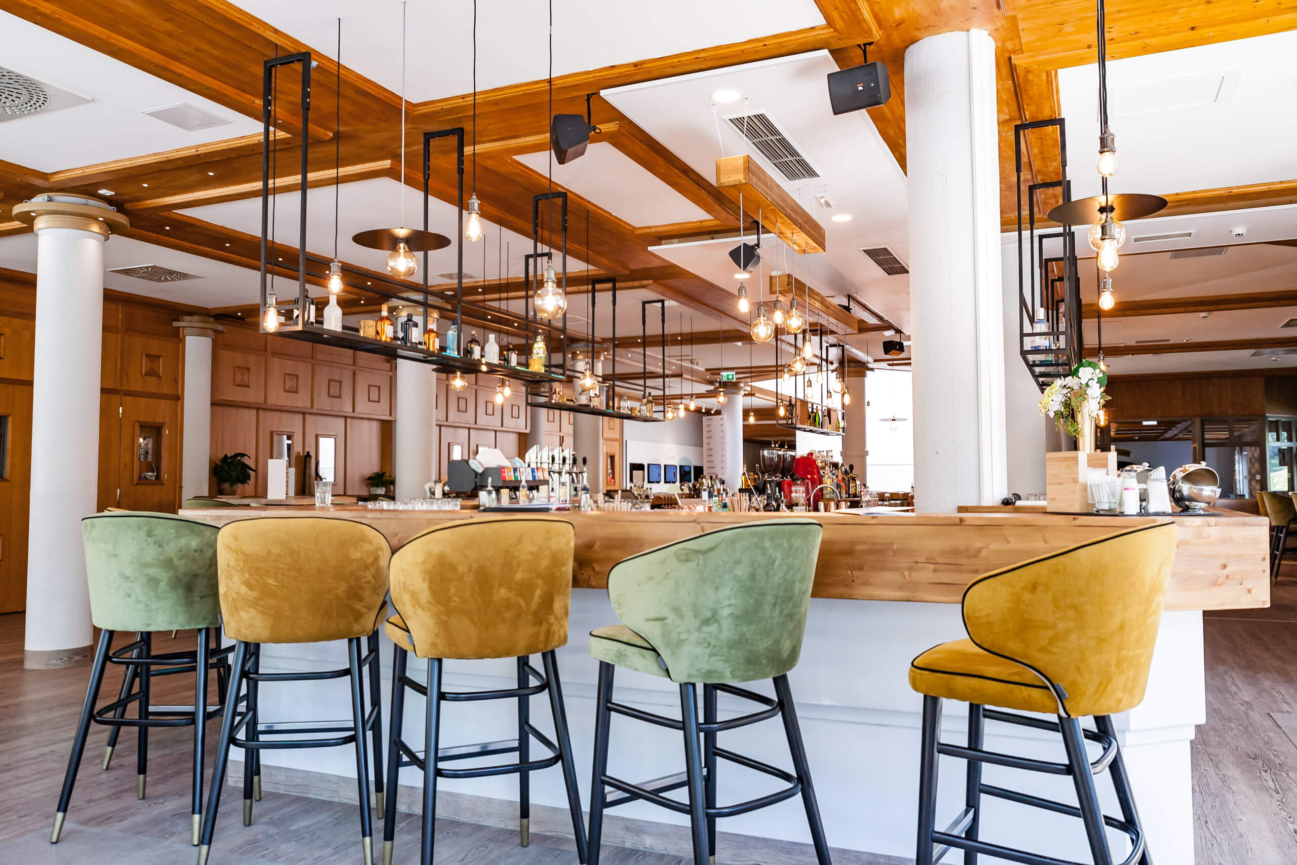 Holzvertäfelte Bar mit stilvollen Hängeleuchten und Sitzmöbeln, passend zur Architektur & Objektanstrahlung.