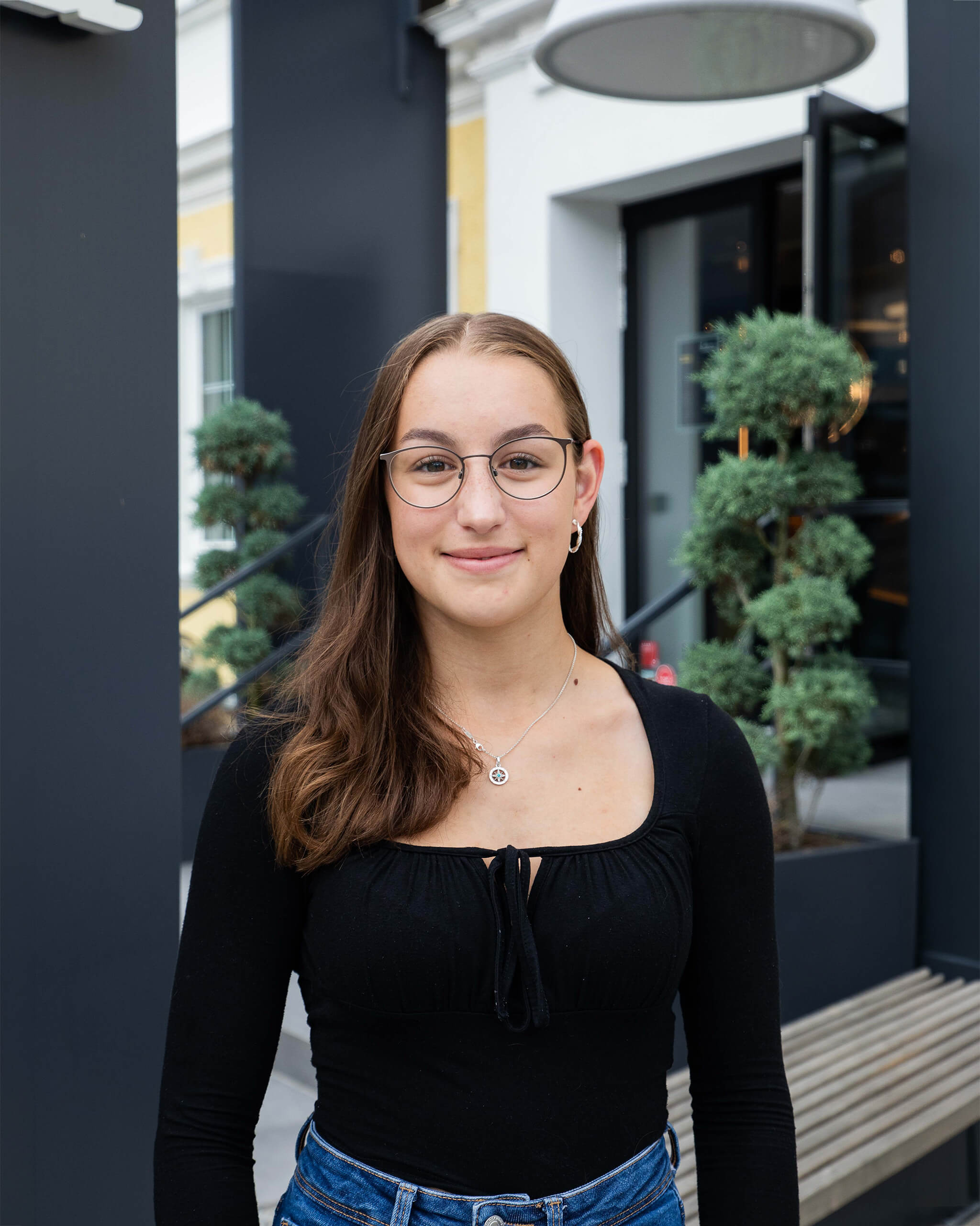 Marlene Mühringer mit Brille und schwarzem Oberteil vor moderner Fassade