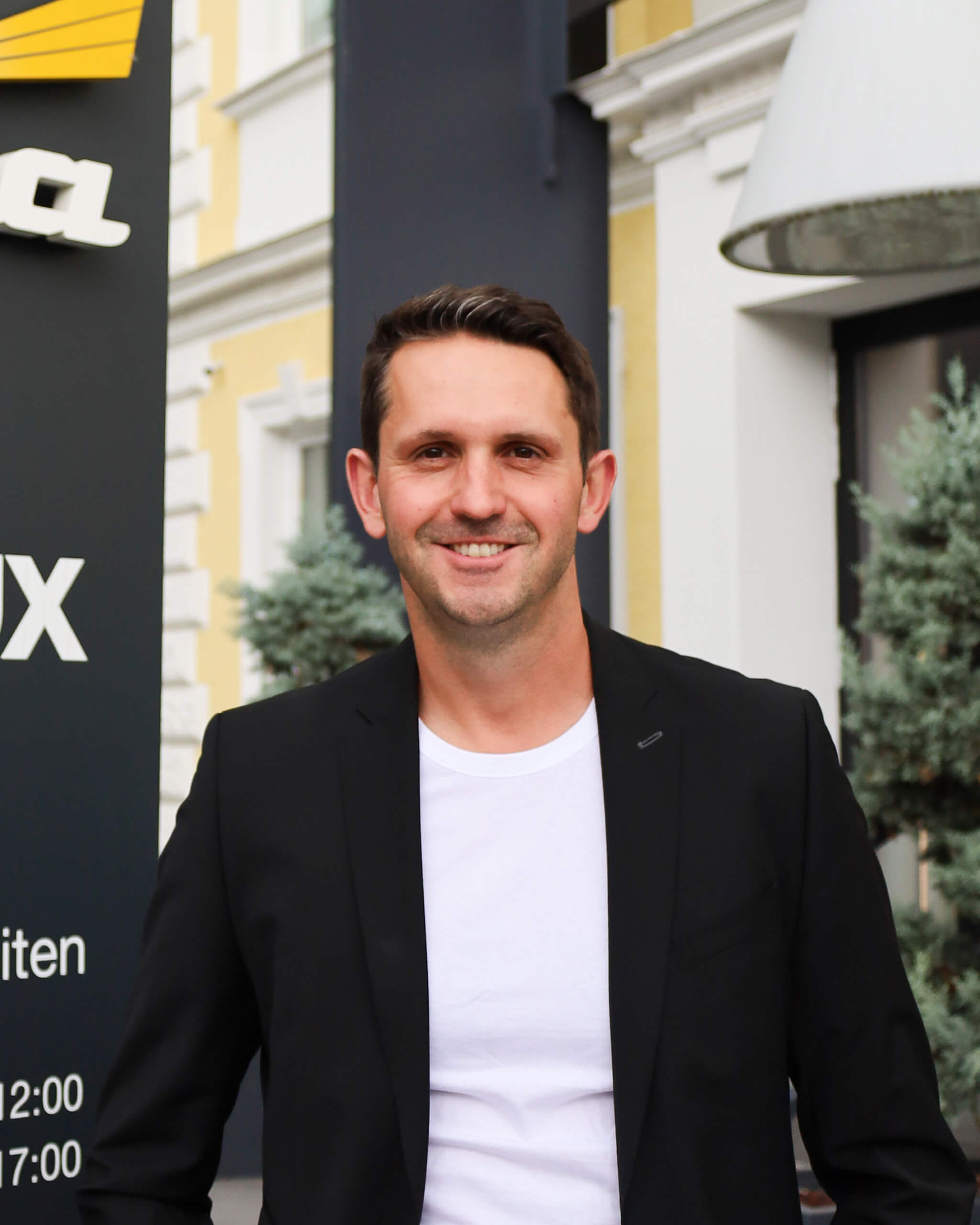 Michael Sandriester vor einem Gebäude mit Beschriftung