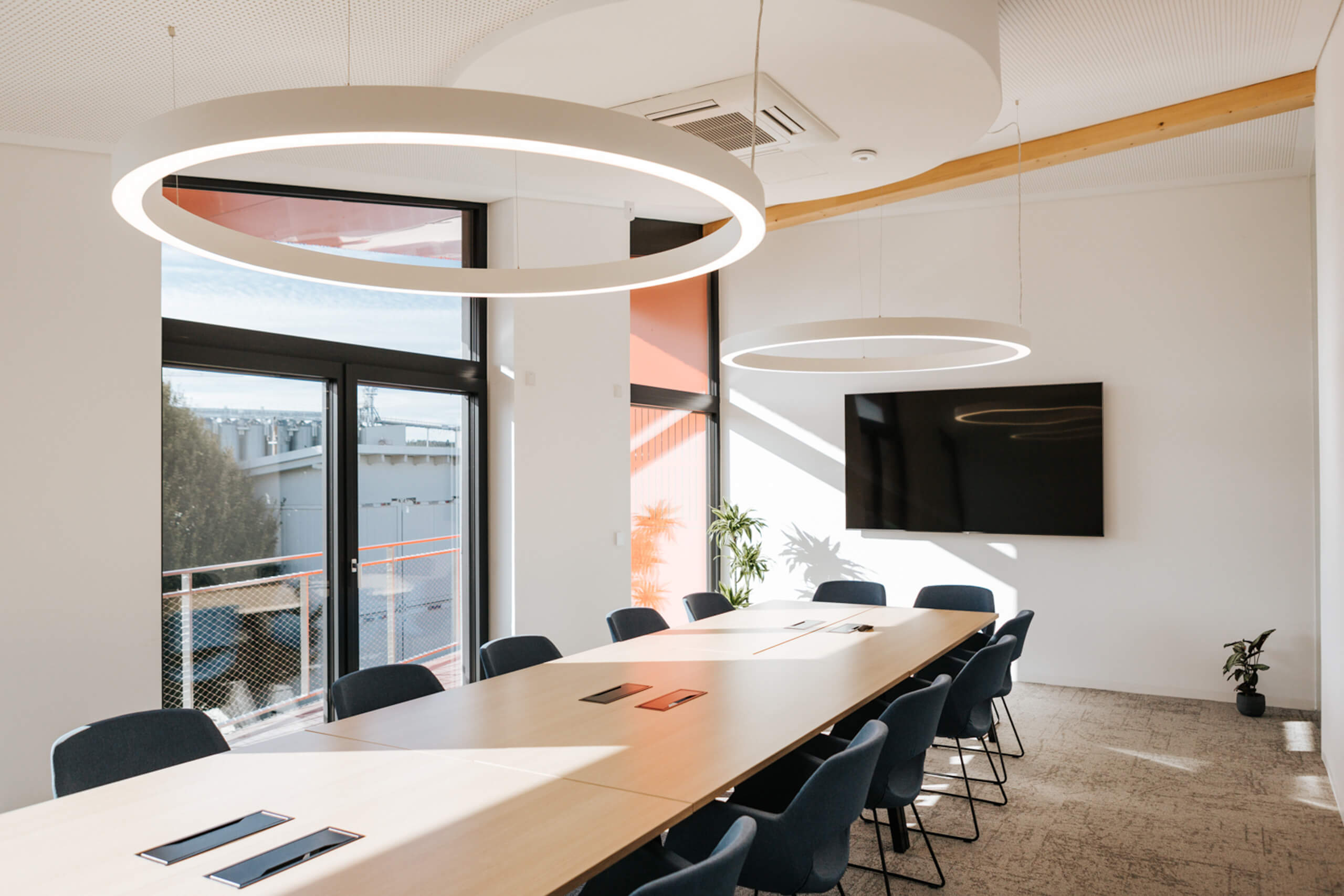 Moderne Bürokonferenz mit heller Beleuchtung und großem Besprechungstisch.