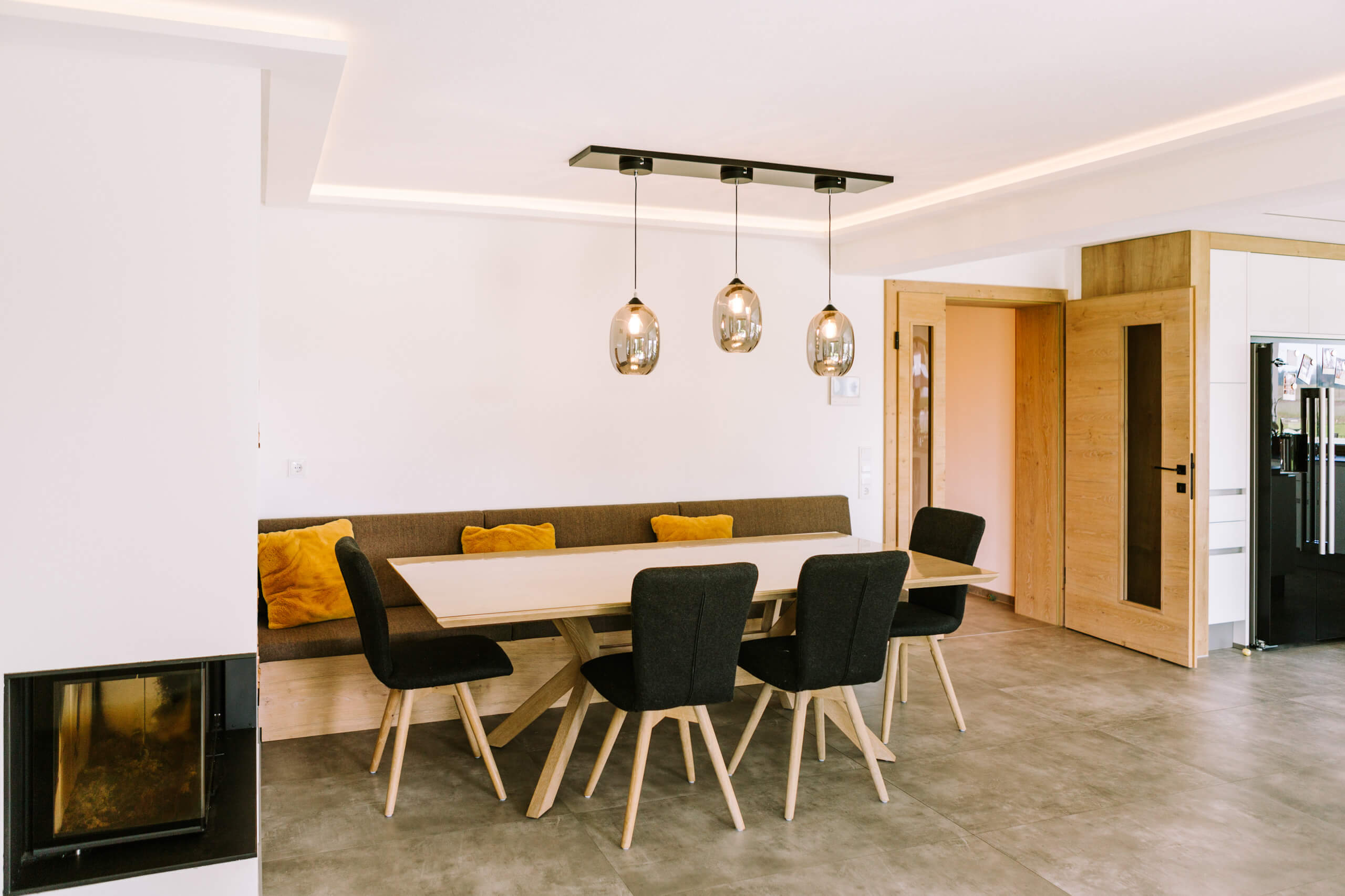 Essbereich mit Eckbank, Holztisch und modernen Pendelleuchten – Lichtplanung von Illumina.