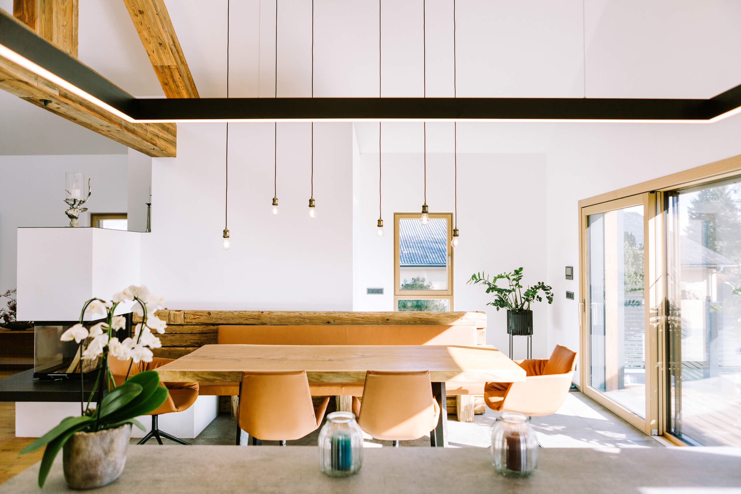 Essbereich mit Holztisch und Sitzbank, beleuchtet durch moderne Pendelleuchten – Lichtplanung Privat.