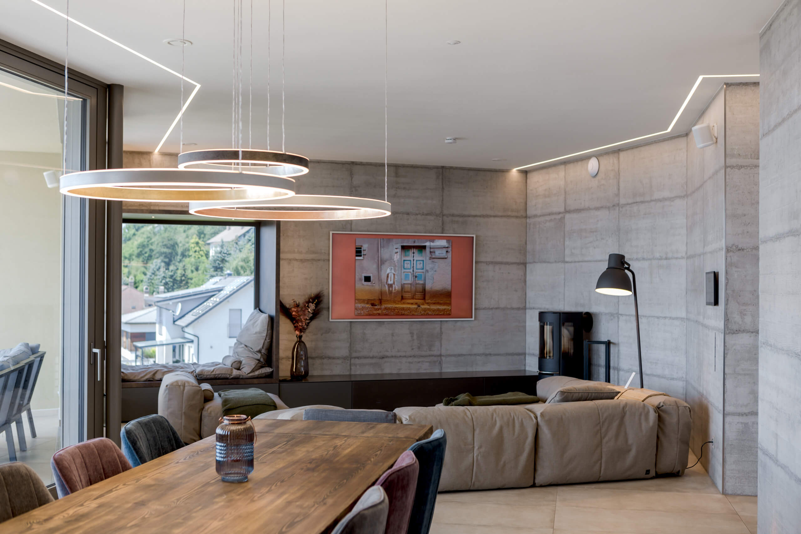 Modernes Wohnzimmer mit Betonwand, gemütlicher Couch und indirekter Beleuchtung – Lichtplanung Österreich