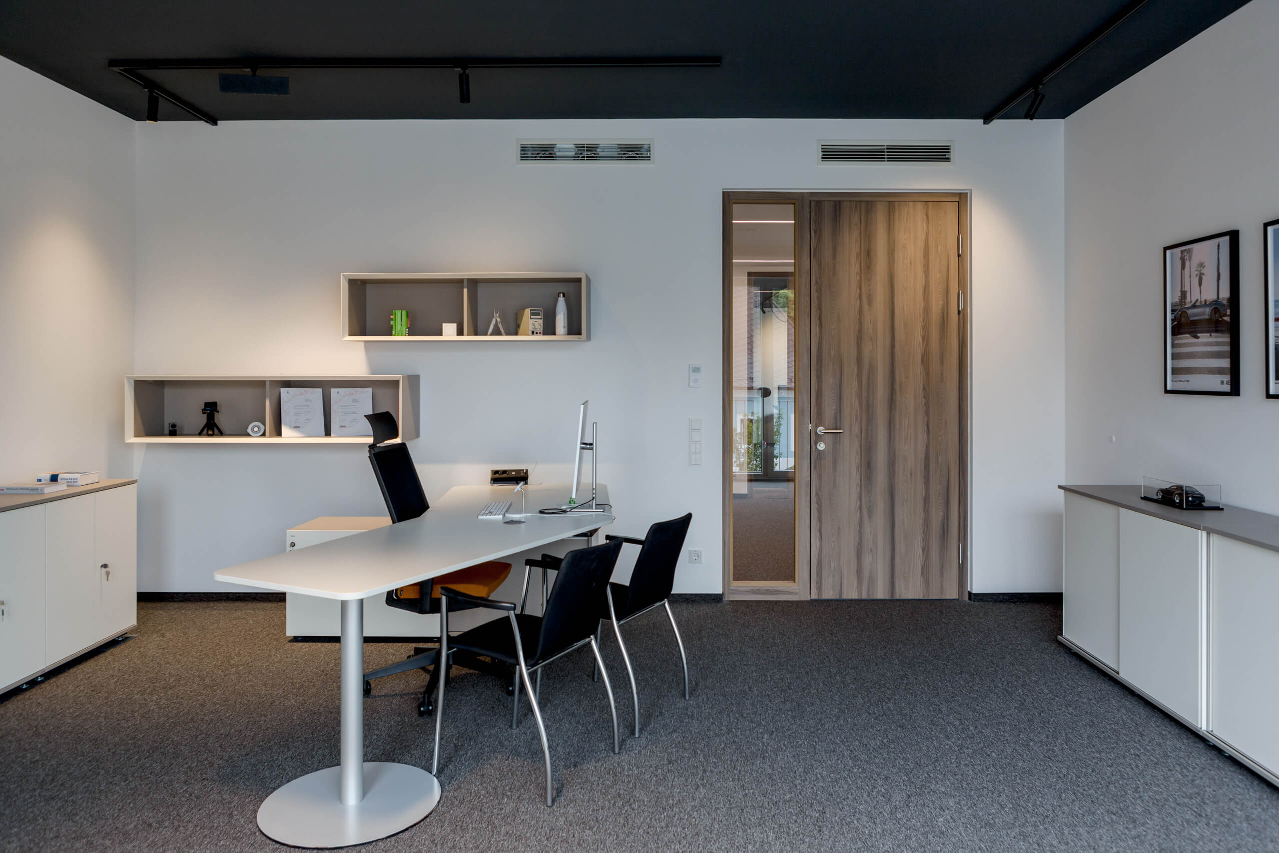 Modernes Büro mit Schreibtisch, Stühlen und Holztür – Lichtplanung von Illumina.