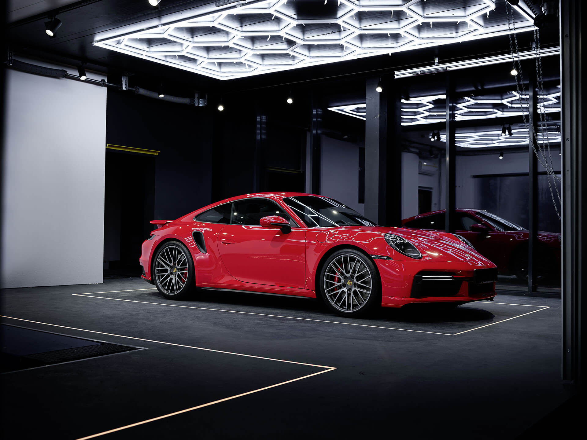 Moderne Gewerbe-Lichtplanung: Rote Sportwagen-Ausstellung in einem beleuchteten Showroom